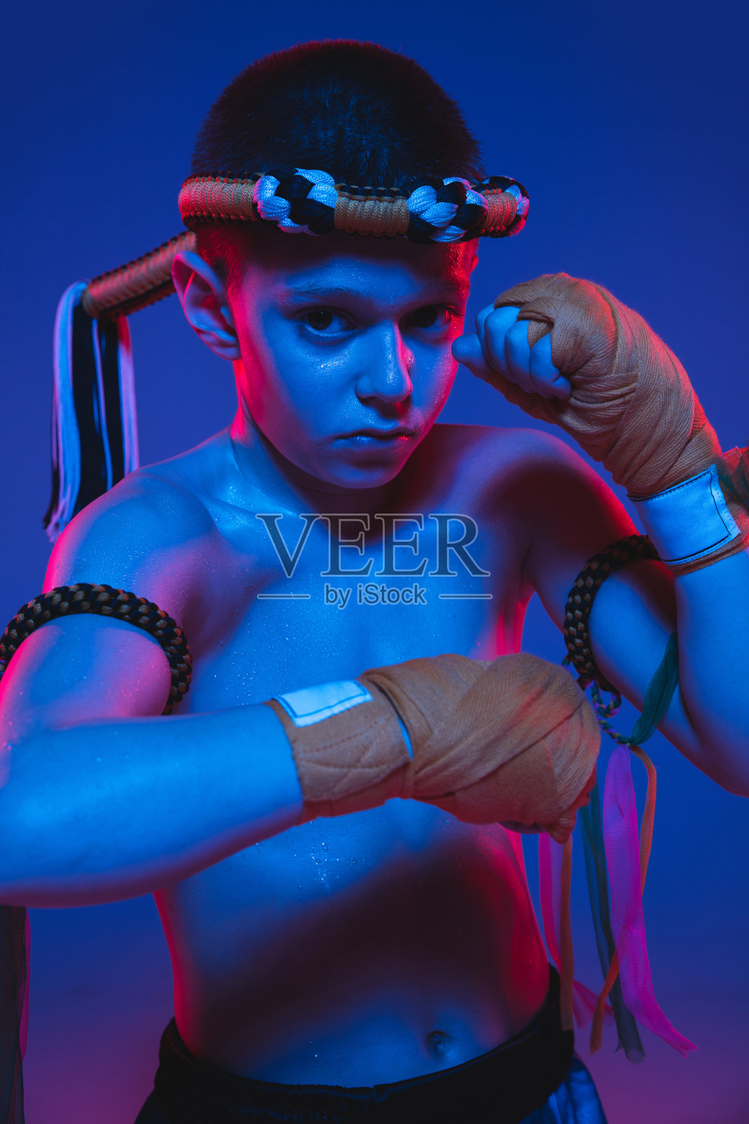 特写的年轻泰国拳击手摆姿势在霓虹灯的蓝色背景。照片摄影图片