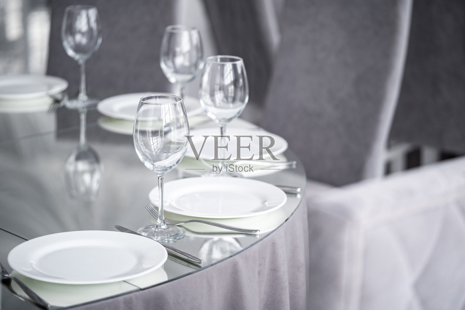 干净透明的酒杯放在镜面的桌面上。服务和时尚简约的晚餐装饰。照片摄影图片