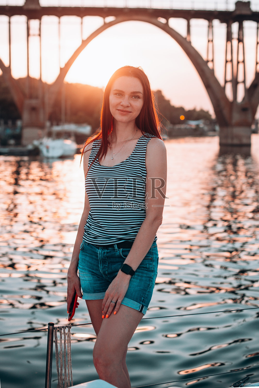 可爱的微笑女人的肖像在橙色日落背景,迷人的生活方式,精彩的游艇之旅照片摄影图片