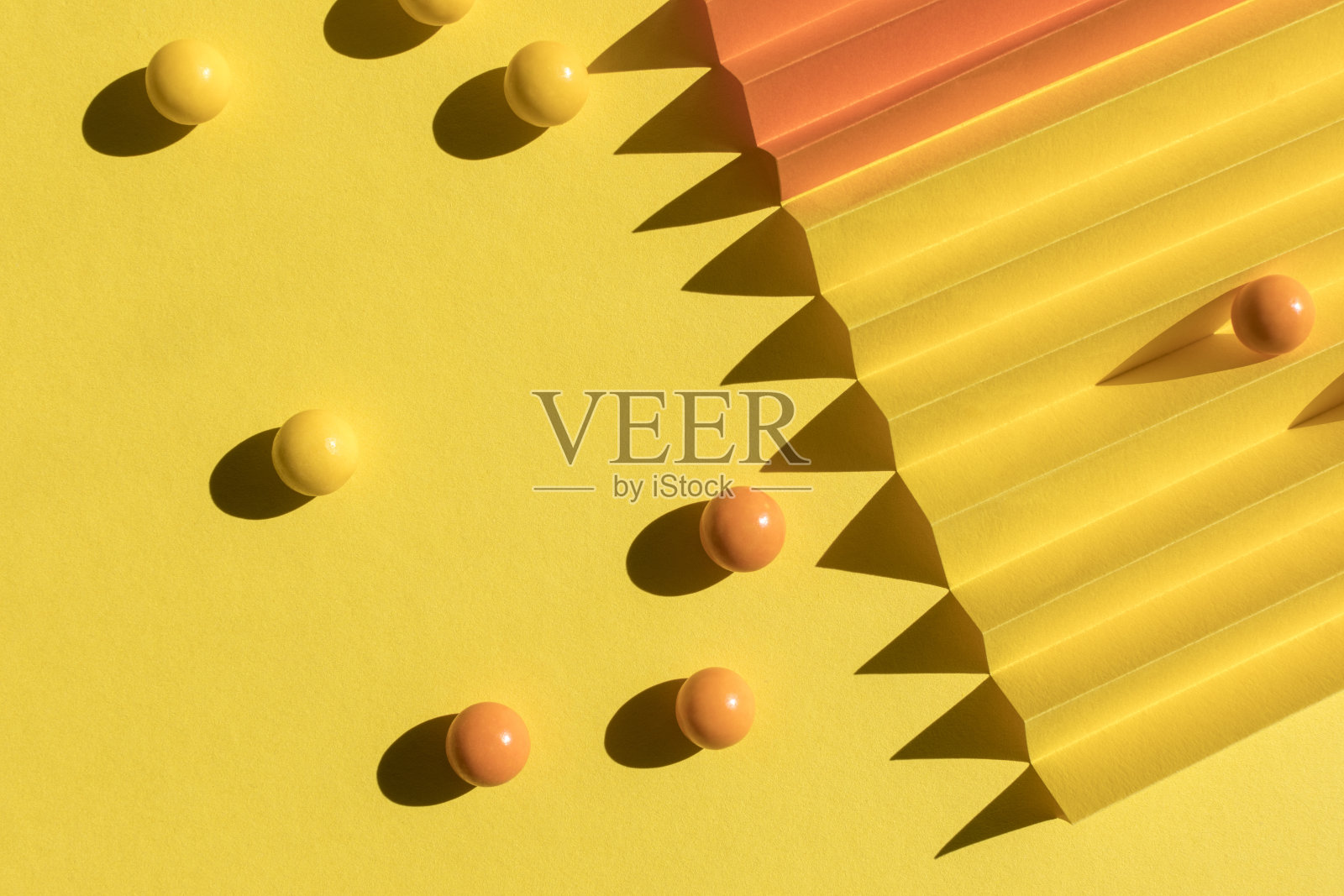 抽象橙色和黄色的纸纹理。折叠的纸有刺眼的阳光阴影,几何形状和线条。照片摄影图片