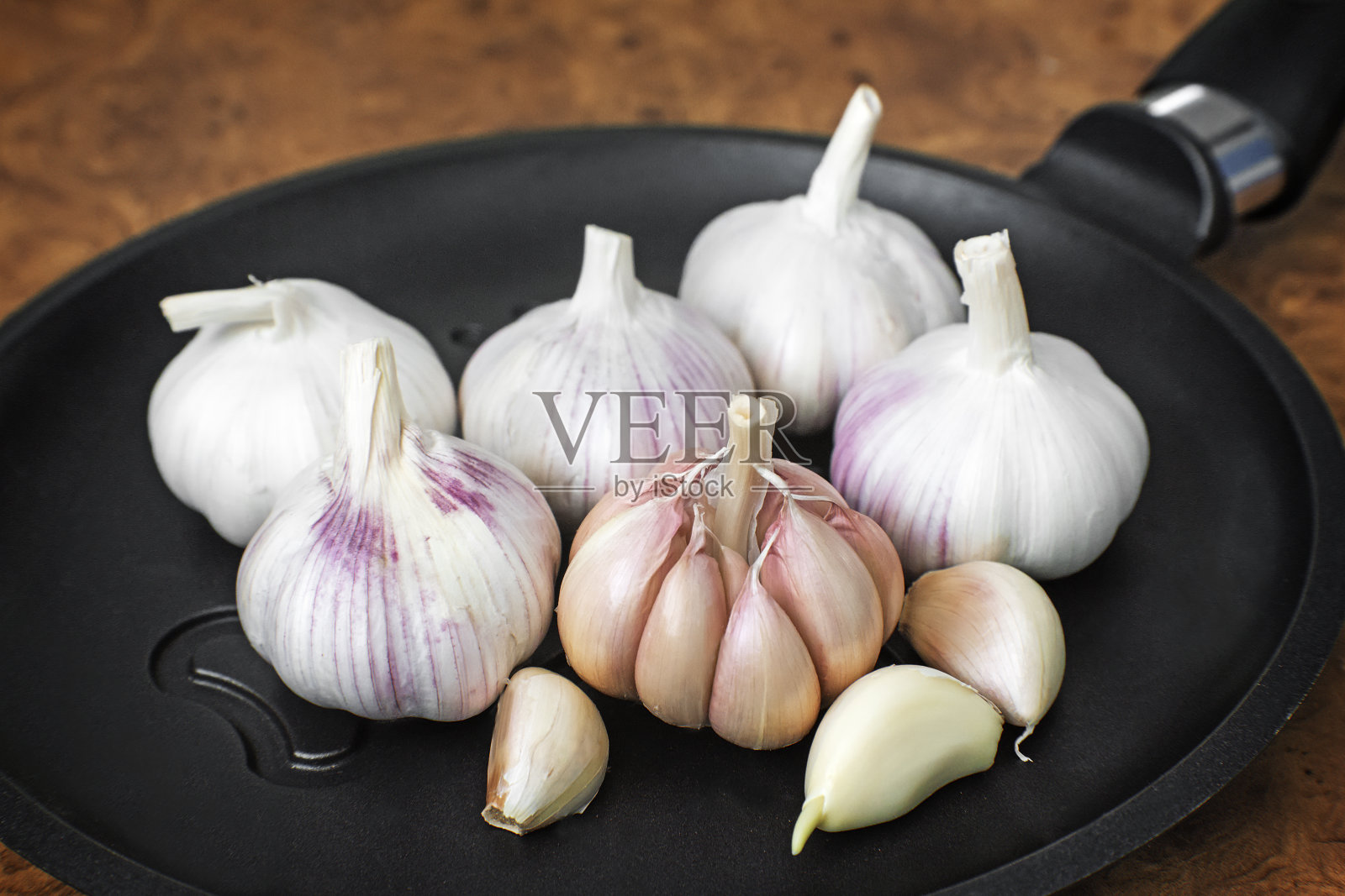 桌上的大蒜和煎锅的特写。照片摄影图片