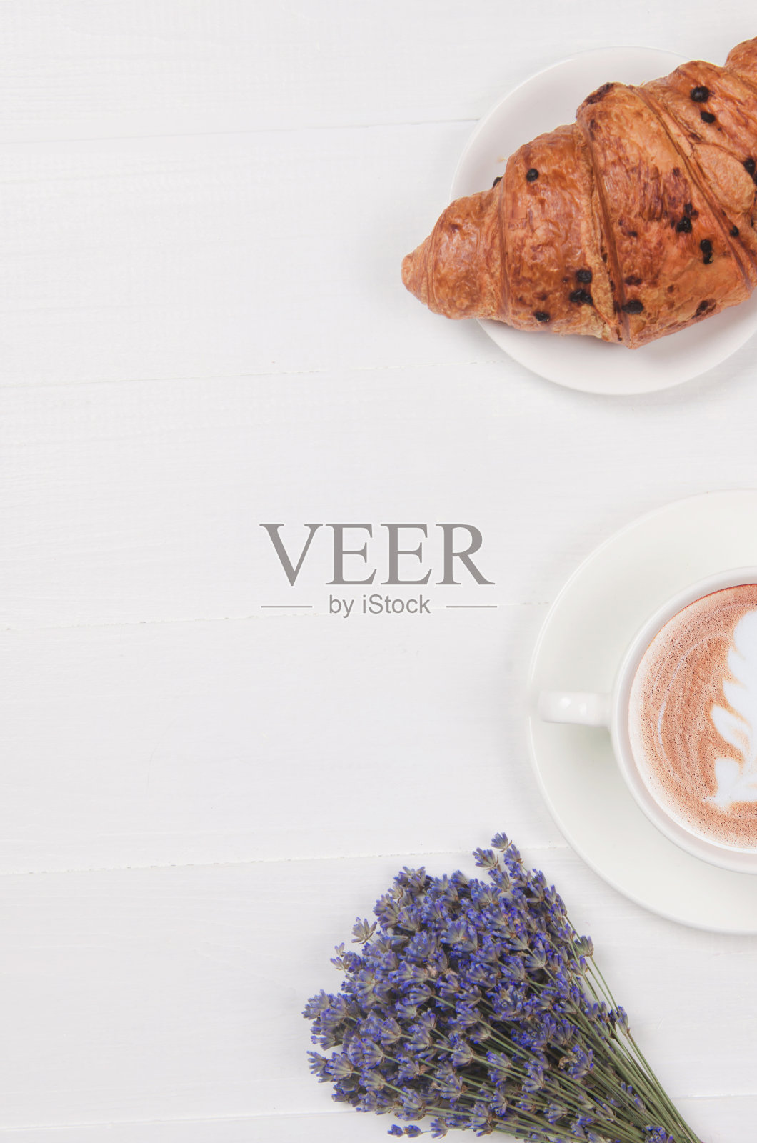 白木桌上放着牛奶咖啡和羊角面包,放着干紫罗兰和薰衣草花照片摄影图片