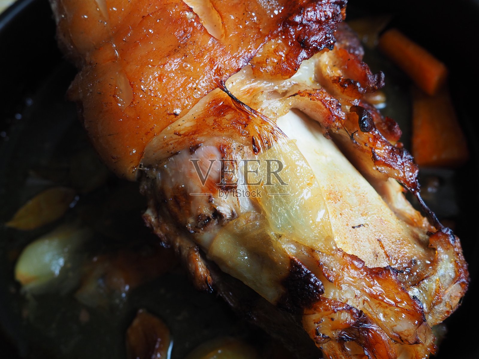 猪蹄放在烤盘上与洋葱,胡萝卜和香料一起烘烤。美味的餐厅或自制菜肴为节日午餐或晚餐。高脂肪高热量的男性食物。Oven-cooked肉照片摄影图片