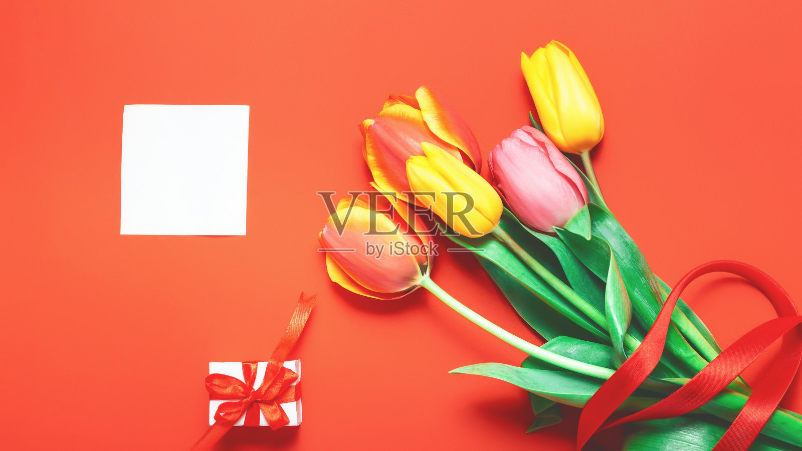 春天的花-一束彩色的郁金香花在橙色的背景。复活节,母亲节模拟贺卡。恭贺或邀请卡与自由的文字空间。照片摄影图片