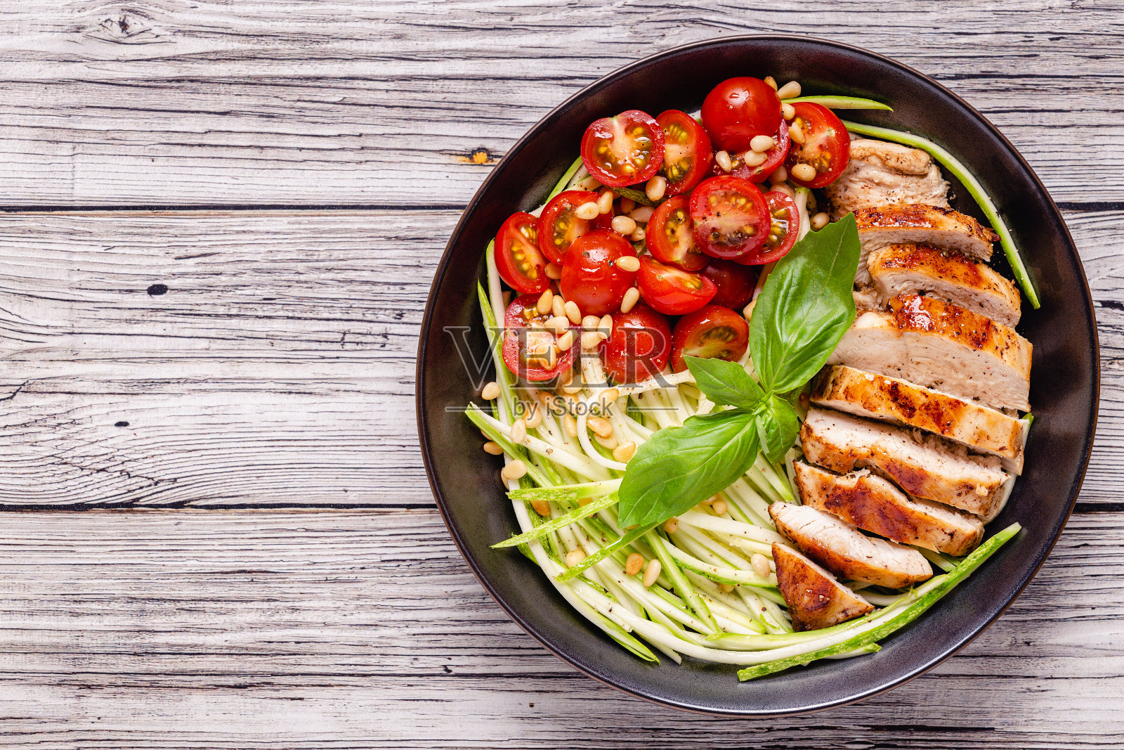 炸鸡片,新鲜蔬菜沙拉,西红柿,西葫芦和松子照片摄影图片