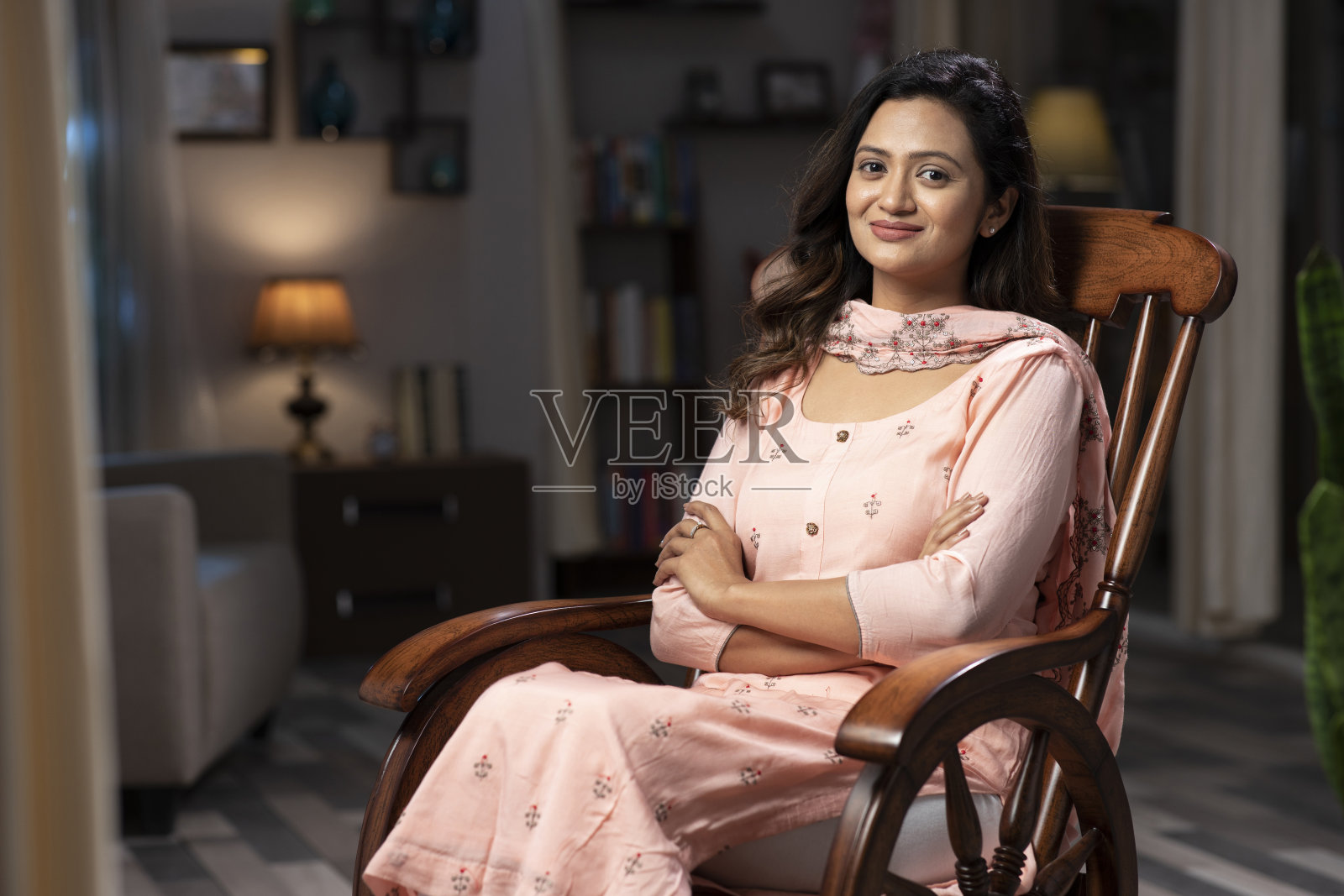 一个年轻女人坐在家里的摇椅上的照片:库存照片照片摄影图片