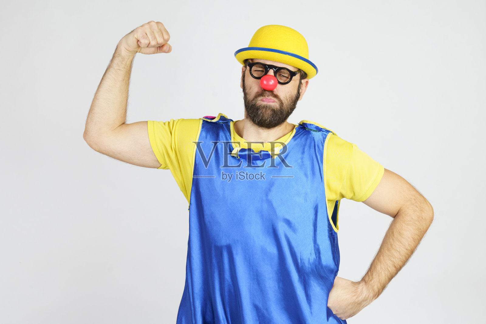 一个穿着亮蓝黄相间衣服的小丑炫耀着他的肌肉照片摄影图片