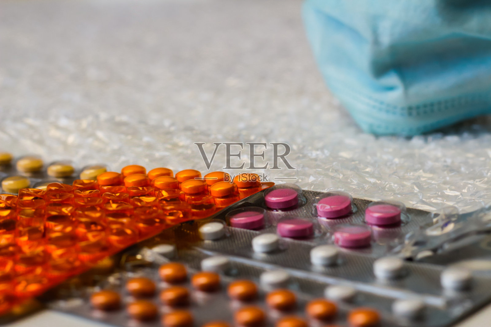 一个隐喻是一张戴着蓝色医用面具的脸,用来观察不同药物的水泡。病毒和大流行会议,隔离概念。抗生素治疗。水平。有选择性的重点照片摄影图片