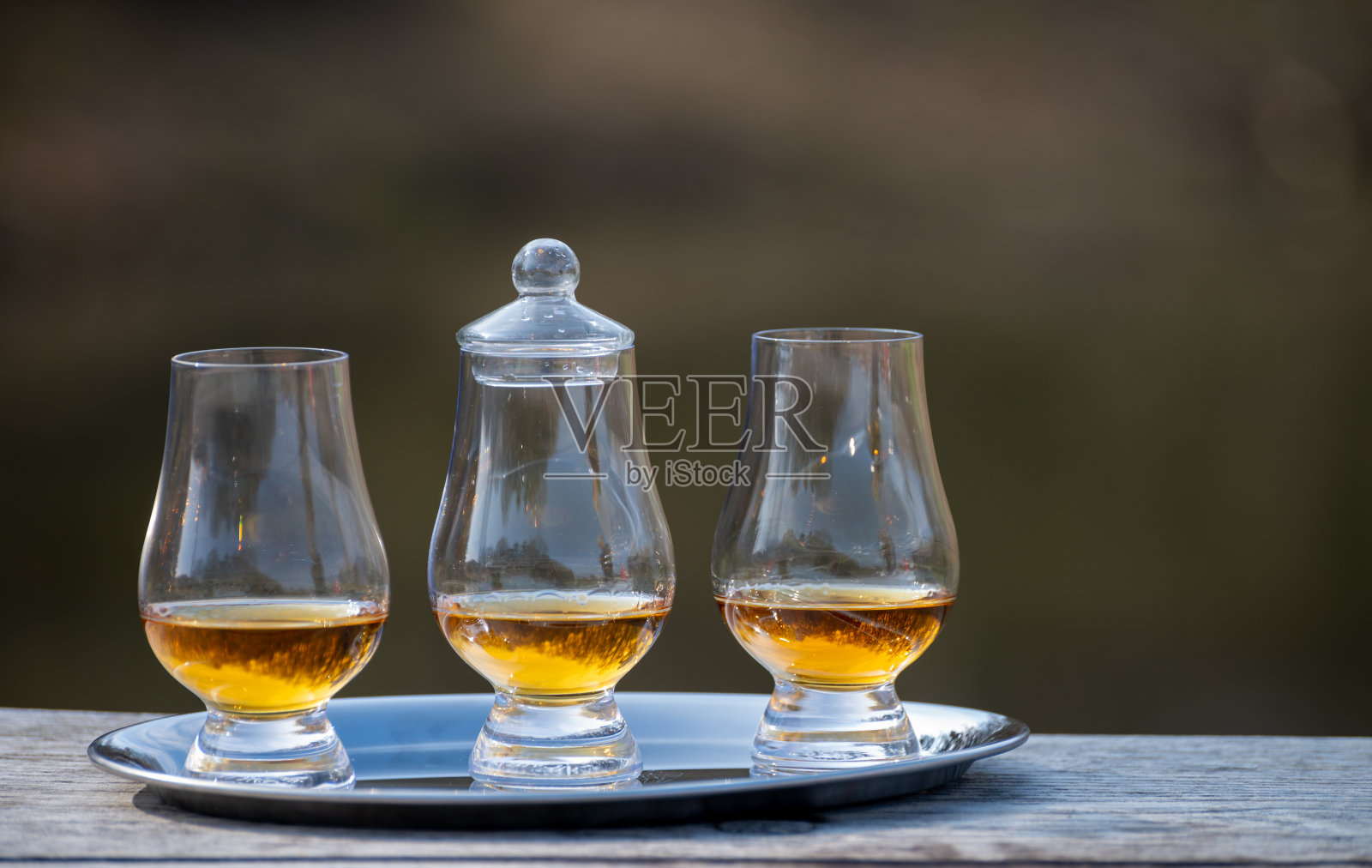 品尝杯苏格兰威士忌烈酒在旧的户外木桌上照片摄影图片