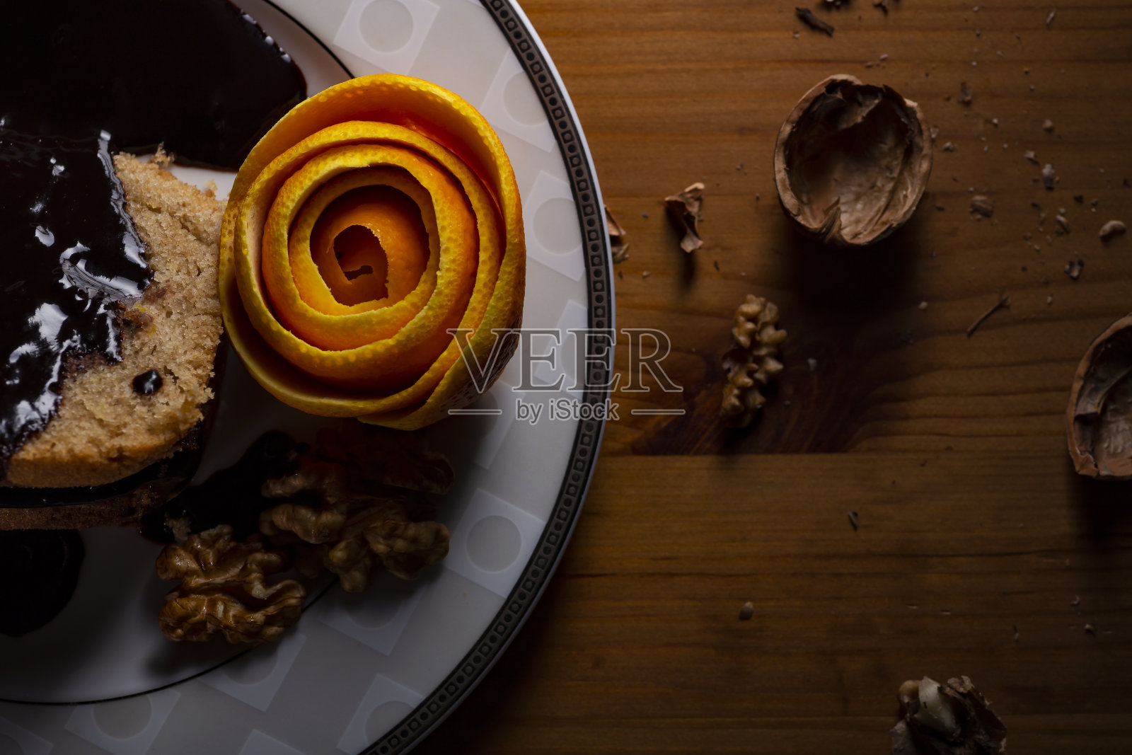 在昏暗的光线下,将巧克力酱橙皮核桃蛋糕放在盘子里。照片摄影图片