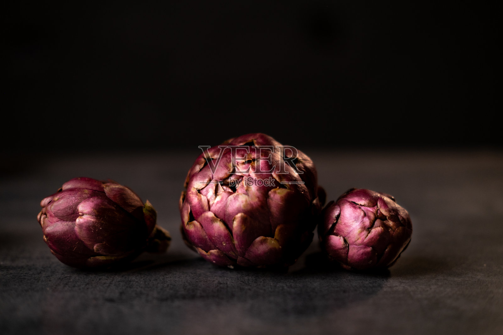 黑色的桌子上放着新鲜成熟的洋蓟。照片摄影图片