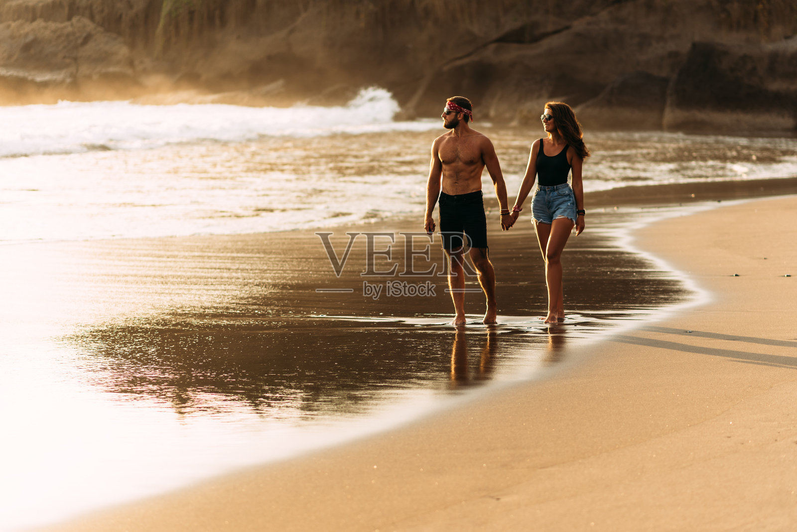 一对幸福的夫妇在巴厘岛的沙滩上散步。一对情侣在日落的海边相爱。一对情侣在度假中相爱。蜜月旅行。一对浪漫的情侣在日落时分享受海滩散步照片摄影图片