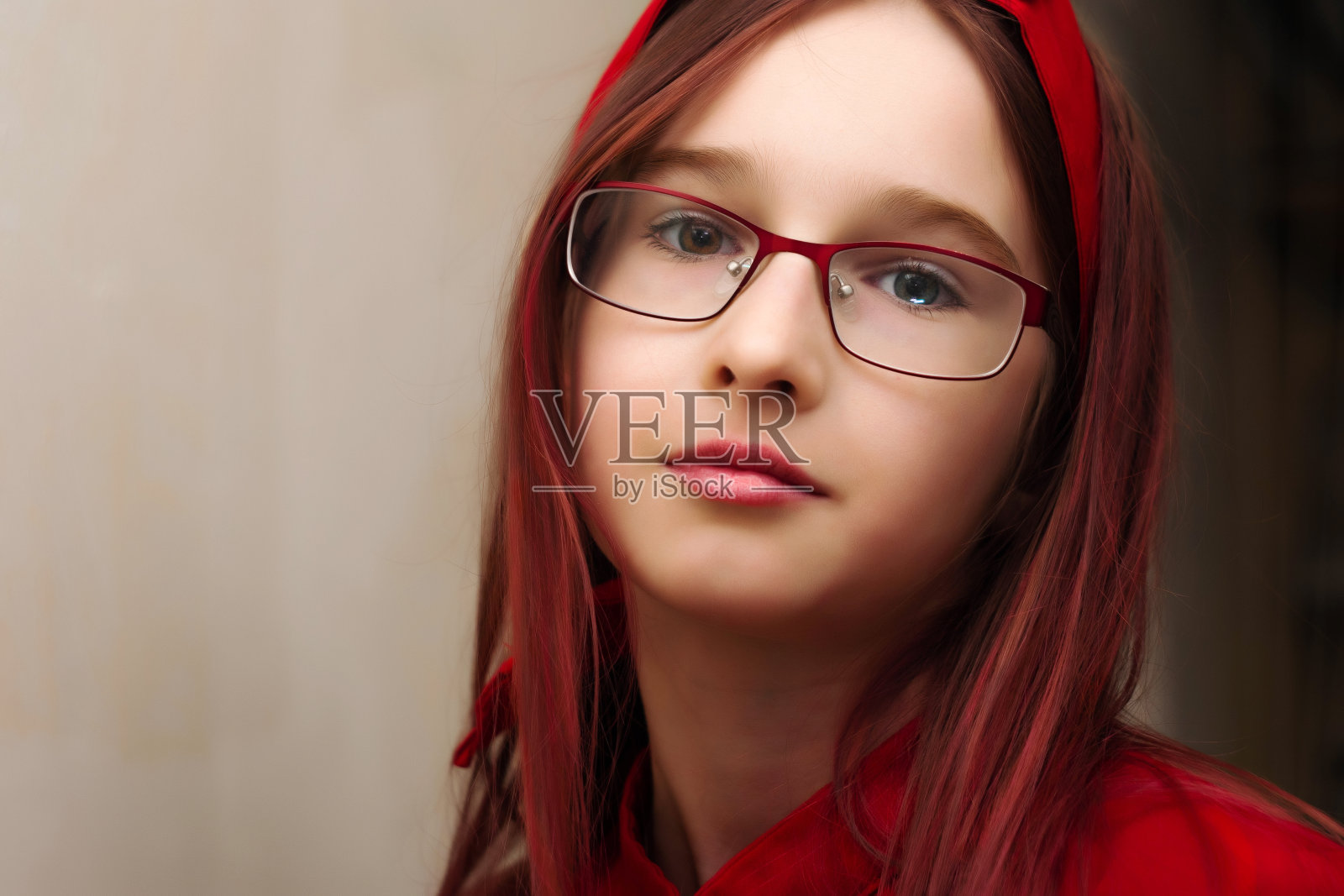 一个漂亮的十几岁的女孩,染红了头发,戴着红眼镜,穿着裙子,戴着头巾。彩色的眼睛。棕色和灰色的眼睛。异色症。一个时尚的青少年的肖像。照片摄影图片