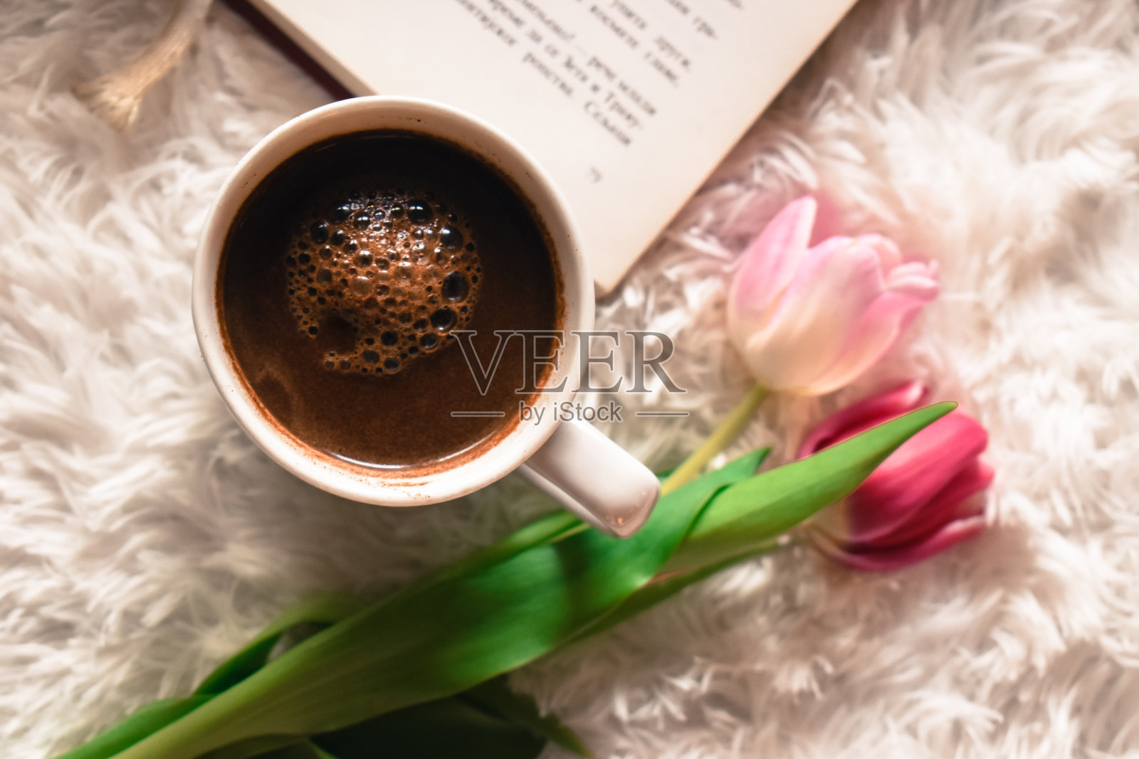 白色地毯上放着咖啡、书和郁金香照片摄影图片