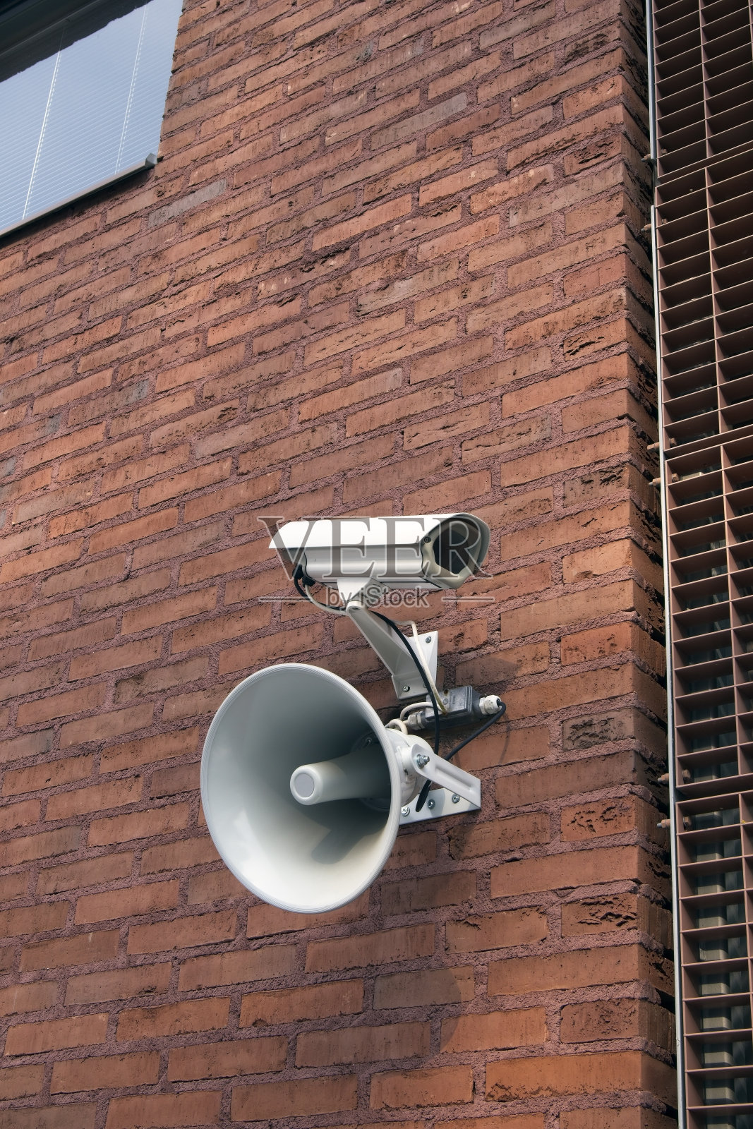 外面砖墙上安装了闭路电视监控摄像头和扩音器照片摄影图片