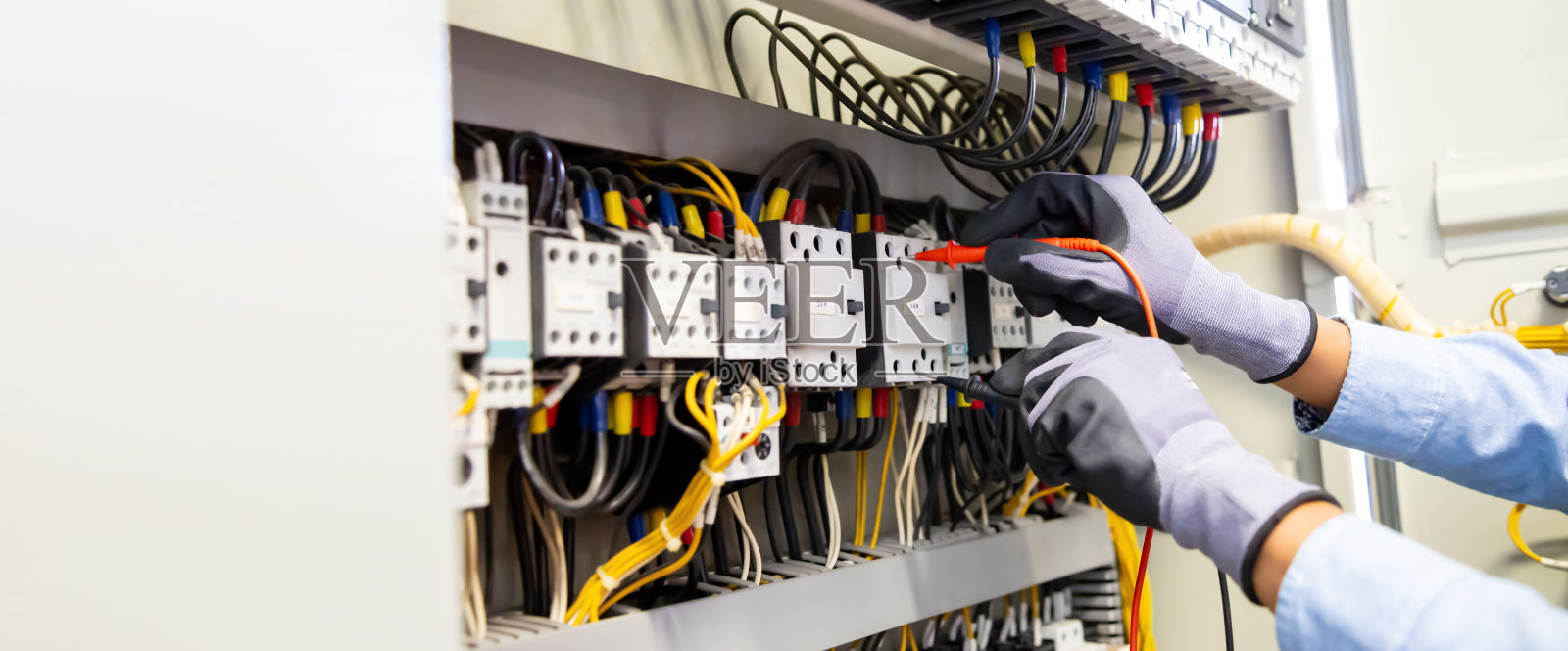 电气工程师利用数字万用表测量设备检查断路器处的电流电压。照片摄影图片