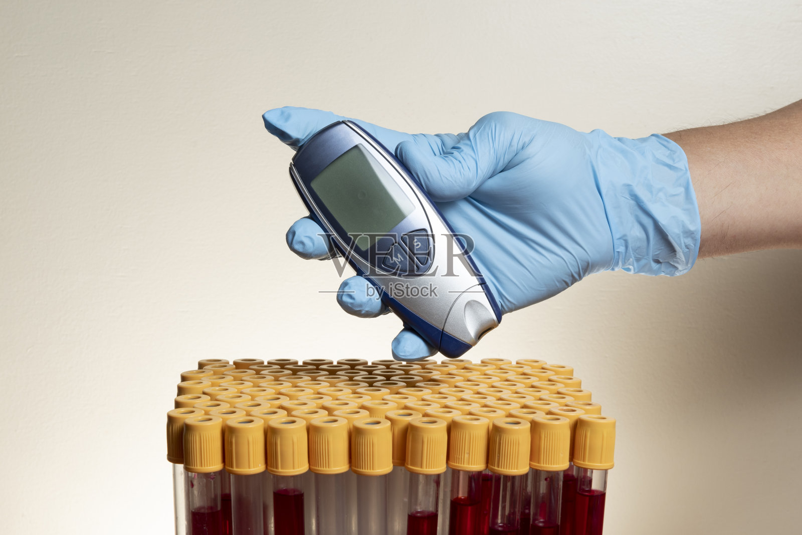 手持保护性丁腈手套,手持带有血液采集管的血糖仪照片摄影图片