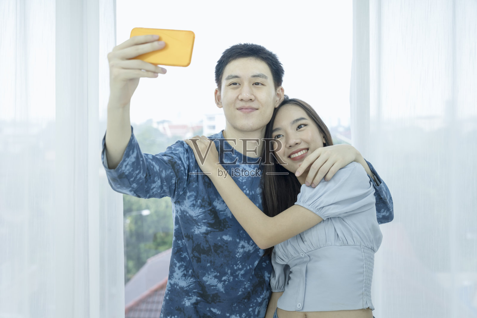 年轻夫妇视频通话和去国外度假。年轻夫妇自拍快乐,并去旅行。亚洲女性和男性在酒店房间或度假村旅行。照片摄影图片