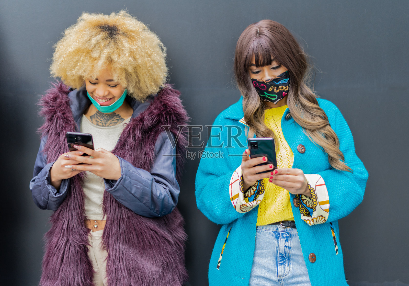 非洲女孩戴着口罩看手机视频-快乐的朋友们玩新的垃圾视频照片摄影图片