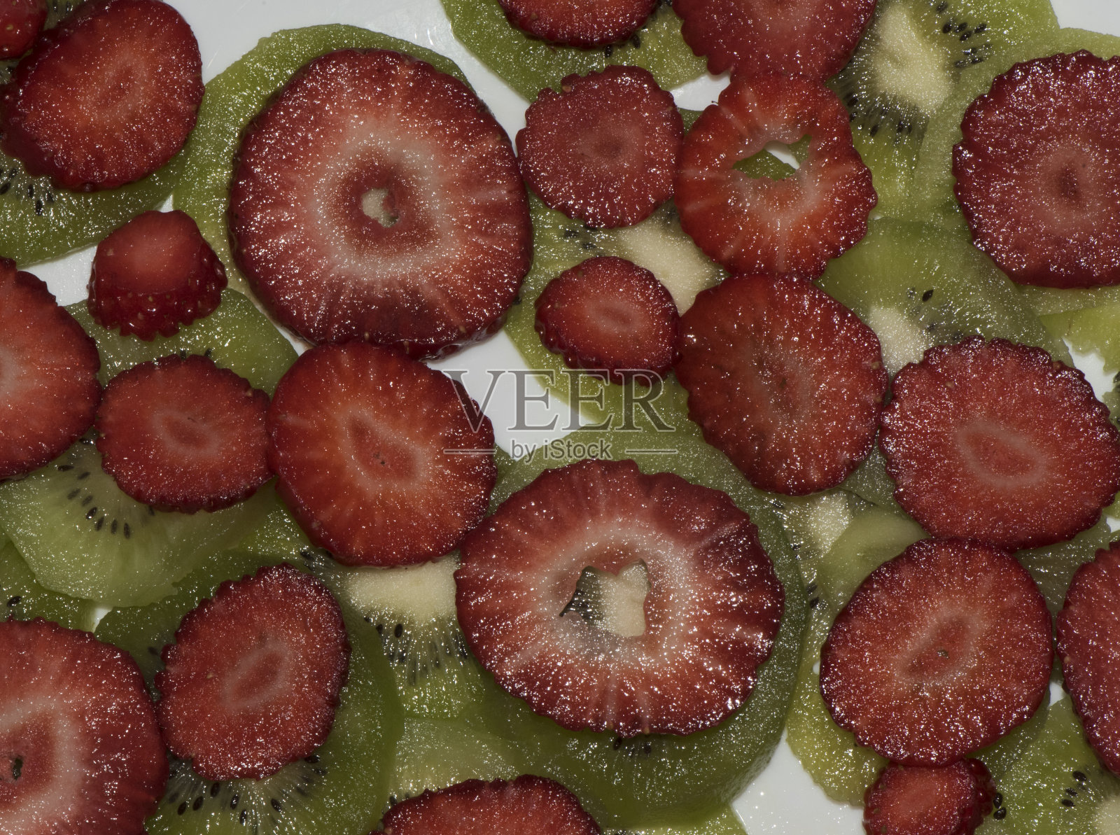 绿色猕猴桃切片显示其条纹和种子新鲜草莓切片显示其红草莓的颜色和种子放在猕猴桃切片上照片摄影图片