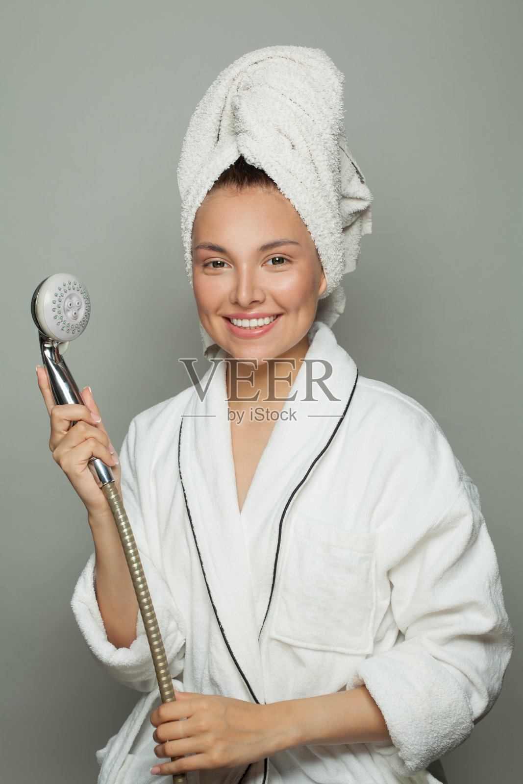 微笑的女人穿着白色浴衣,一边淋浴一边唱歌照片摄影图片