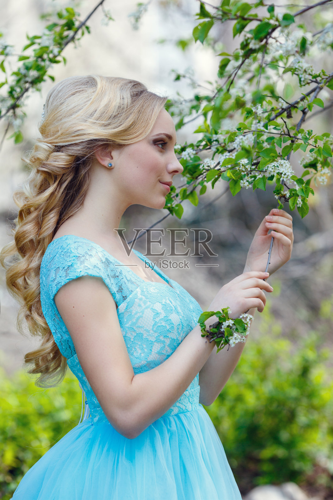 美丽的金发年轻女子穿着时髦的衣服在春天的公园散步。照片摄影图片