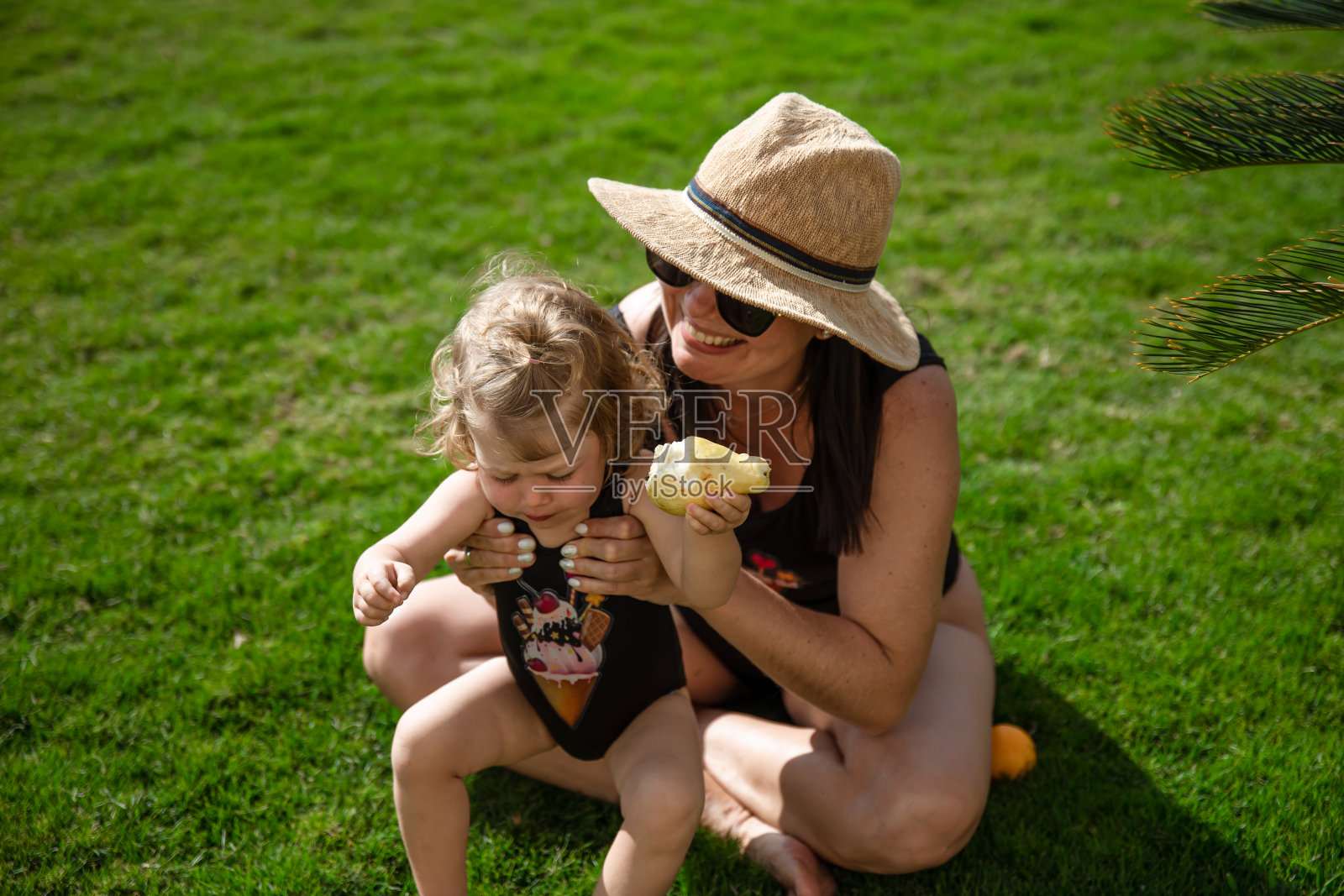 夏天,小女孩和妈妈们在棕榈树下的草地上照片摄影图片