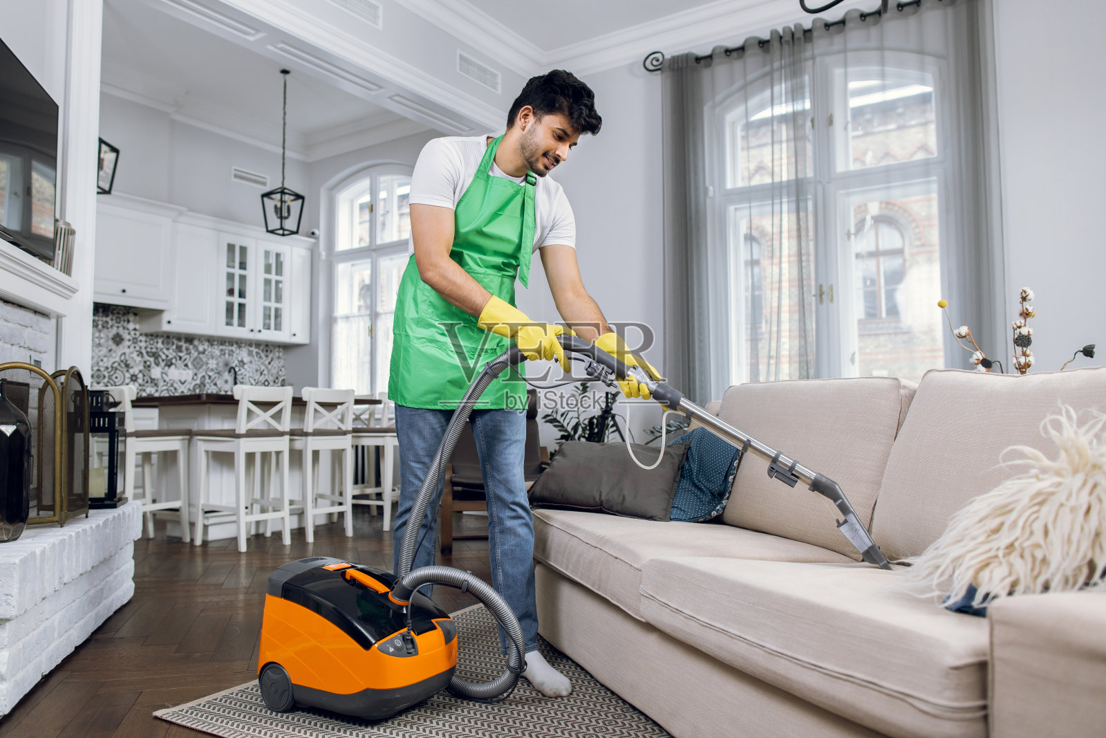 印度男子用吸尘器清洁沙发照片摄影图片