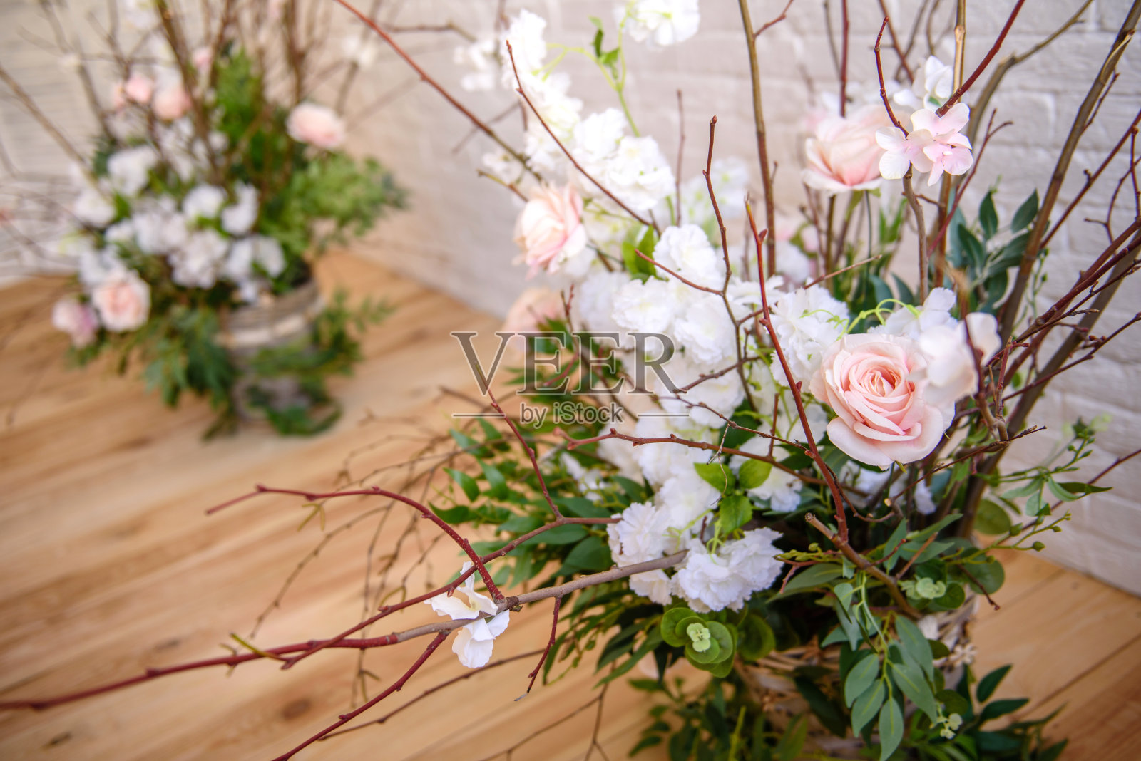 以白色砖墙为背景,用漂亮的粉红色和白色的花篮装饰树枝照片摄影图片