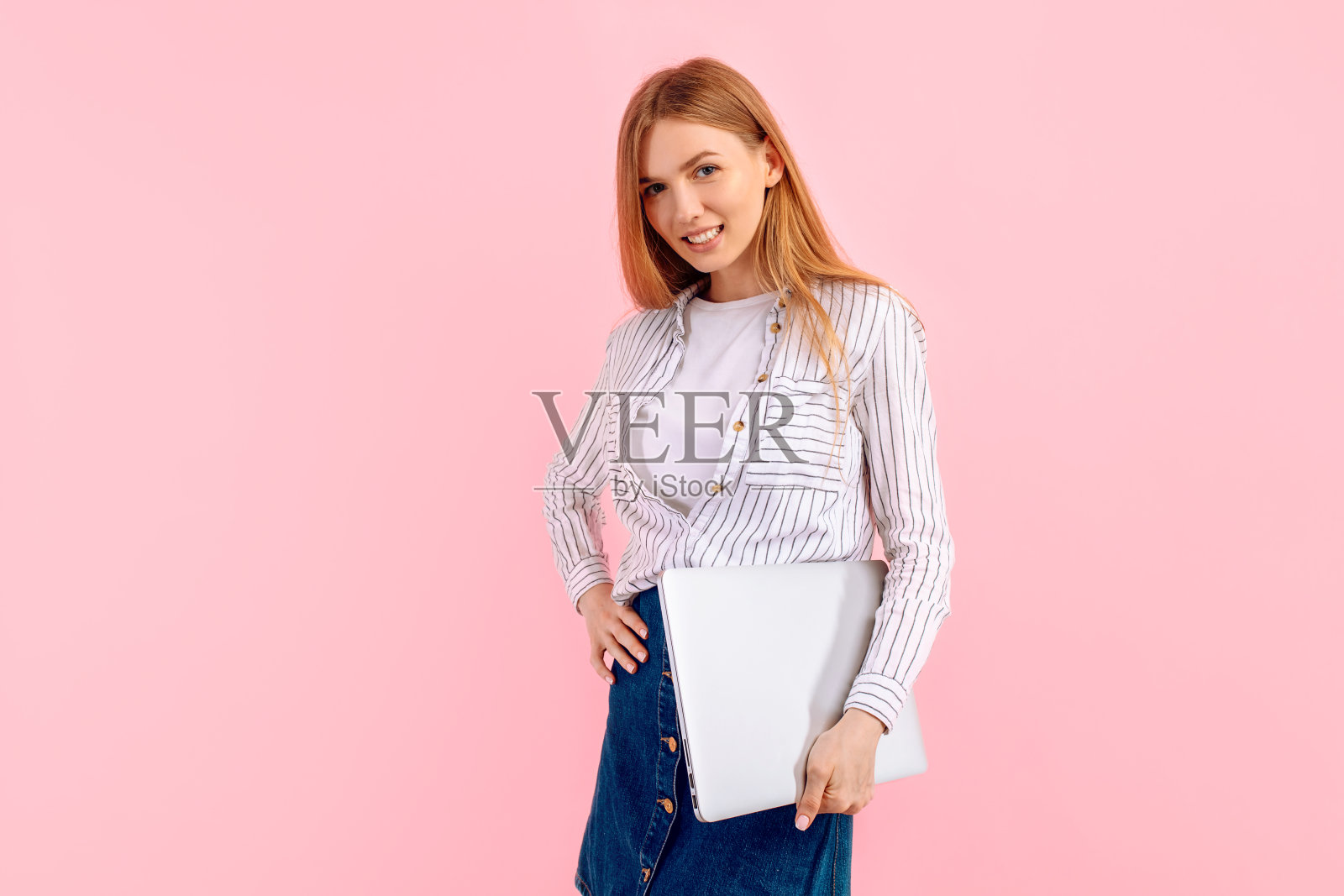 开朗的年轻女子使用笔记本电脑隔离在粉红色的背景照片摄影图片