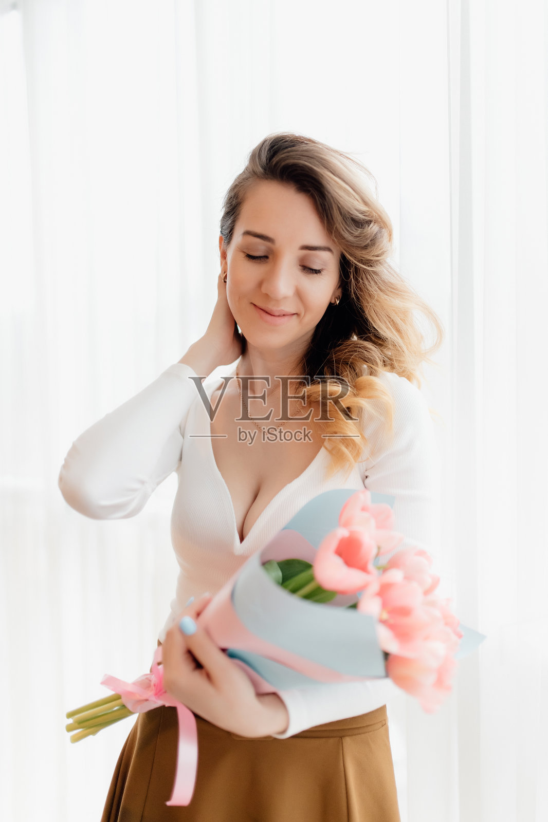 漂亮的金发美女,捧着郁金香花。春天的肖像。女孩手里拿着鲜艳的粉红色花朵照片摄影图片