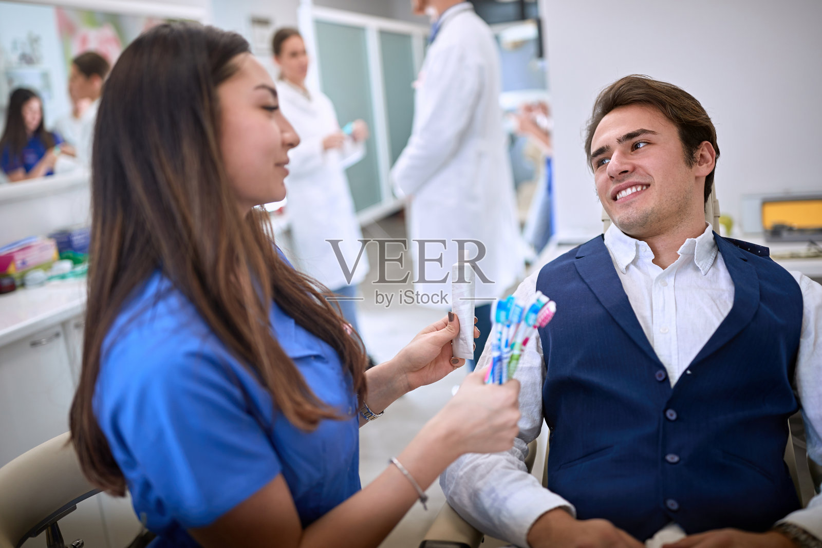 牙医向病人展示牙刷和牙膏照片摄影图片