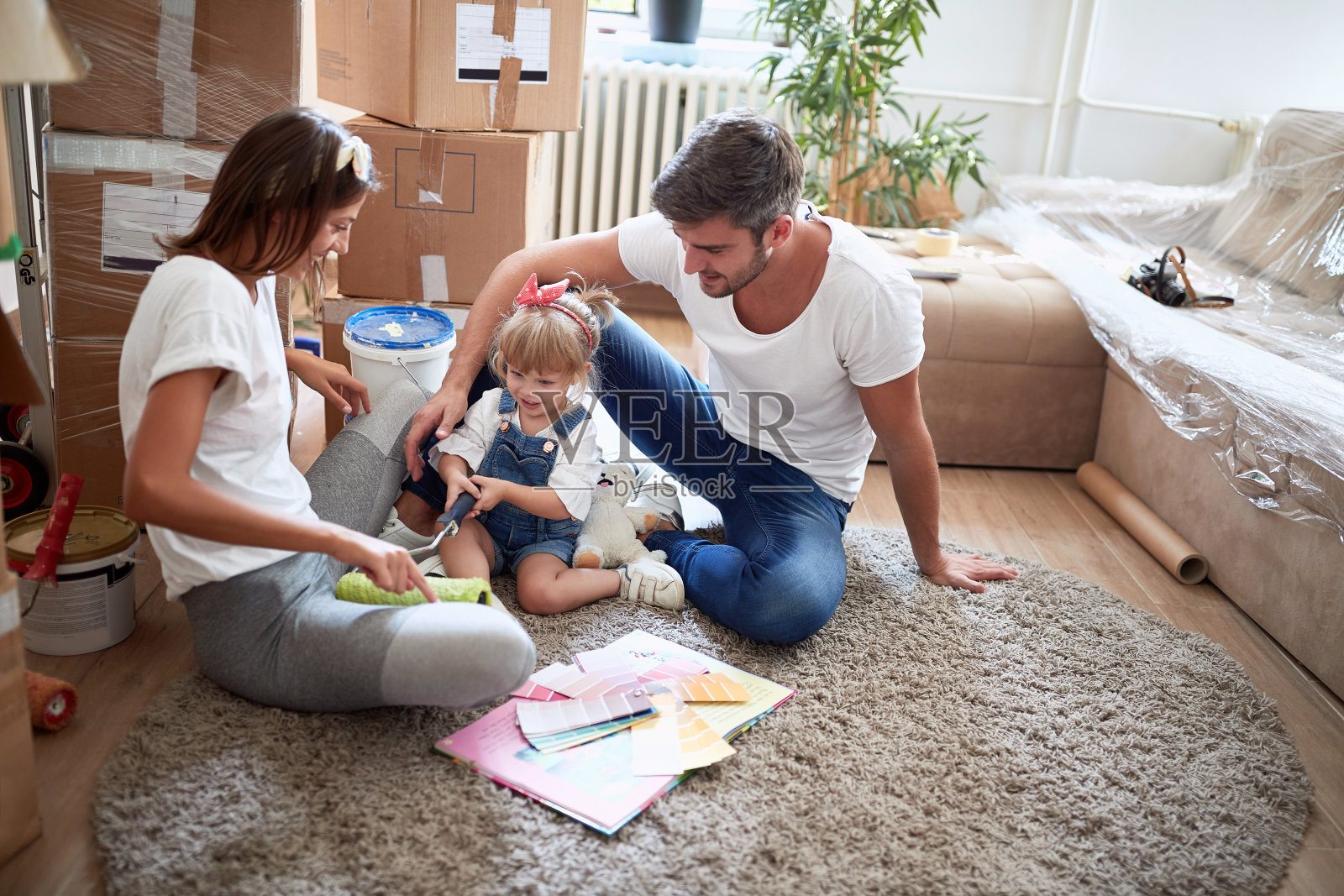 年轻的三口之家在新公寓的地板上玩耍。新的公寓,新的开始,新的概念照片摄影图片