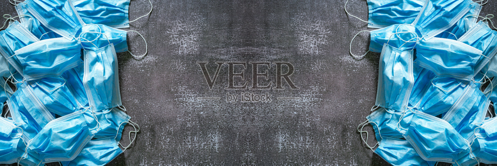 丢弃在灰色沥青上的蓝色医用口罩横幅。垃圾背景与复制空间。处理和回收问题照片摄影图片