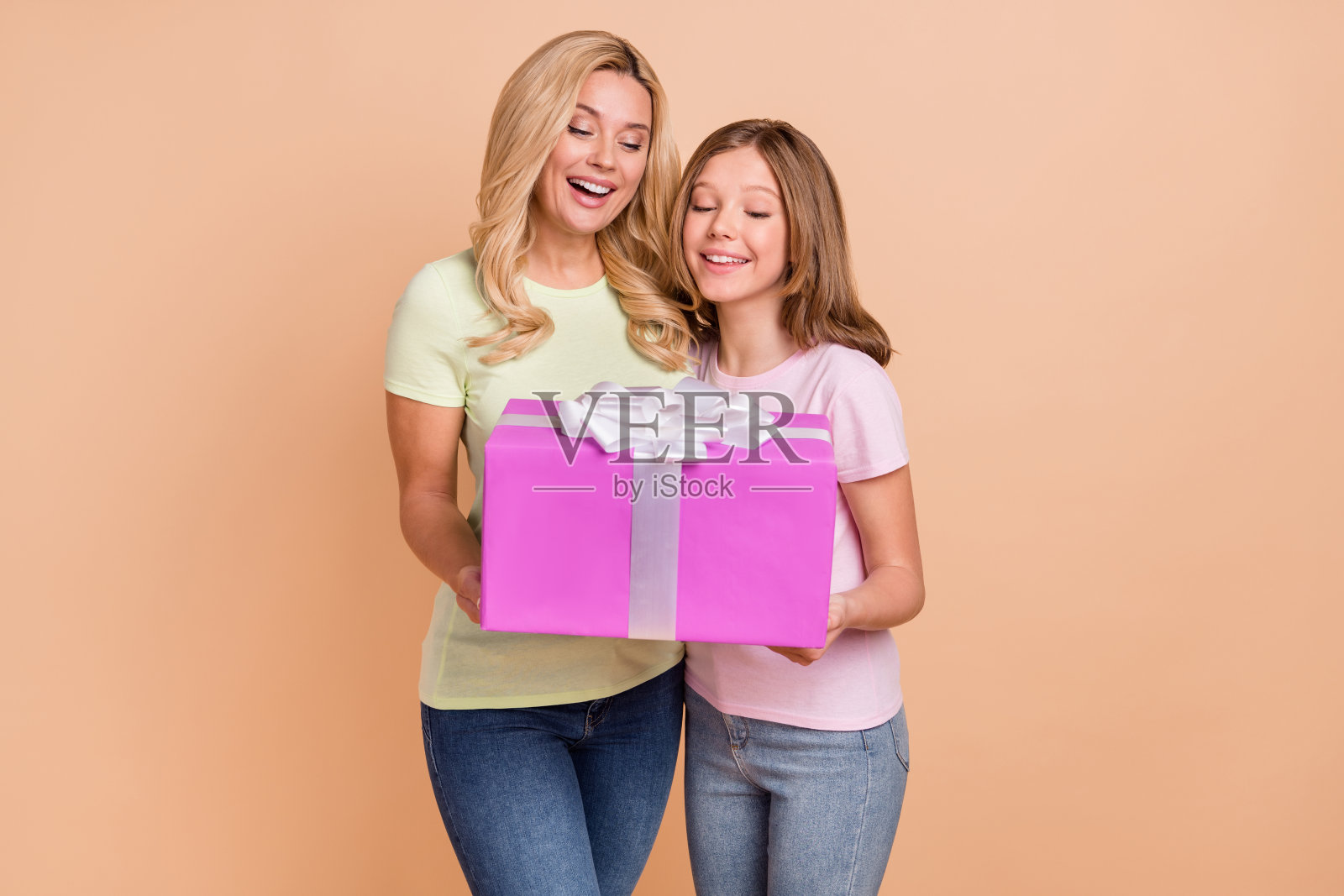 照片迷人的女士迷人的女孩看起来感兴趣的手臂抱着礼盒孤立在米色背景照片摄影图片