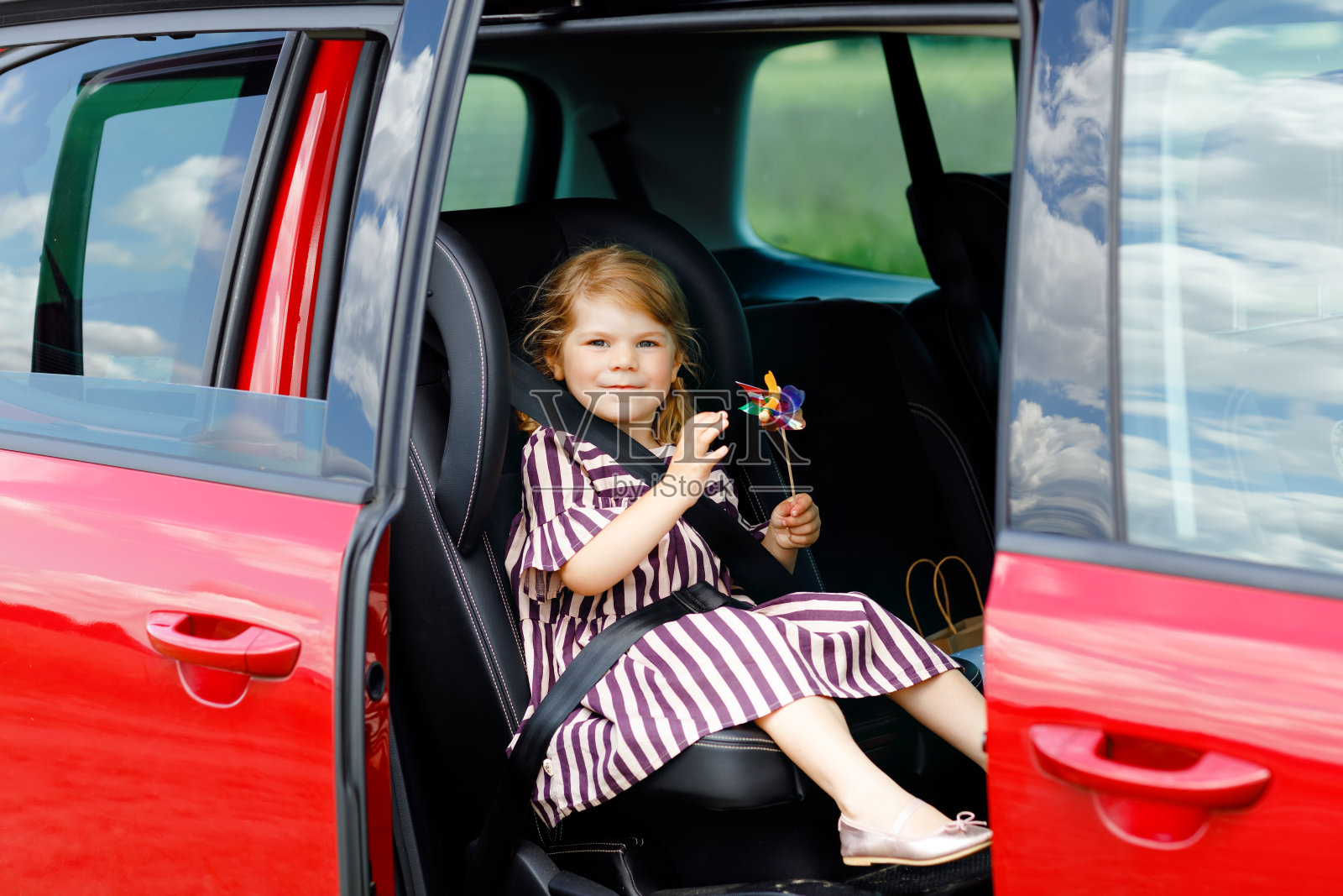 可爱的蹒跚学步的小女孩坐在汽车座椅上,看着窗外的自然和交通。小孩子开车旅行。儿童安全在路上。暑期家庭旅行和度假照片摄影图片