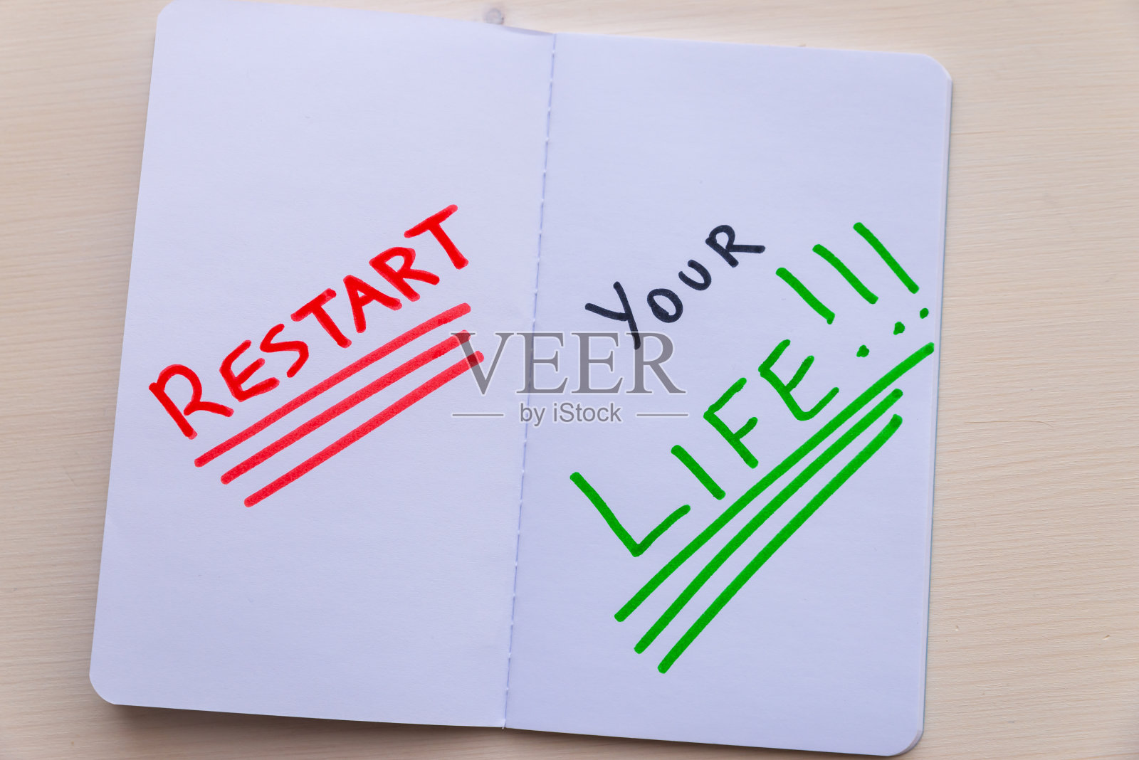 用红、黑、绿写着“重新开始你的生活”的白页笔记本。照片摄影图片