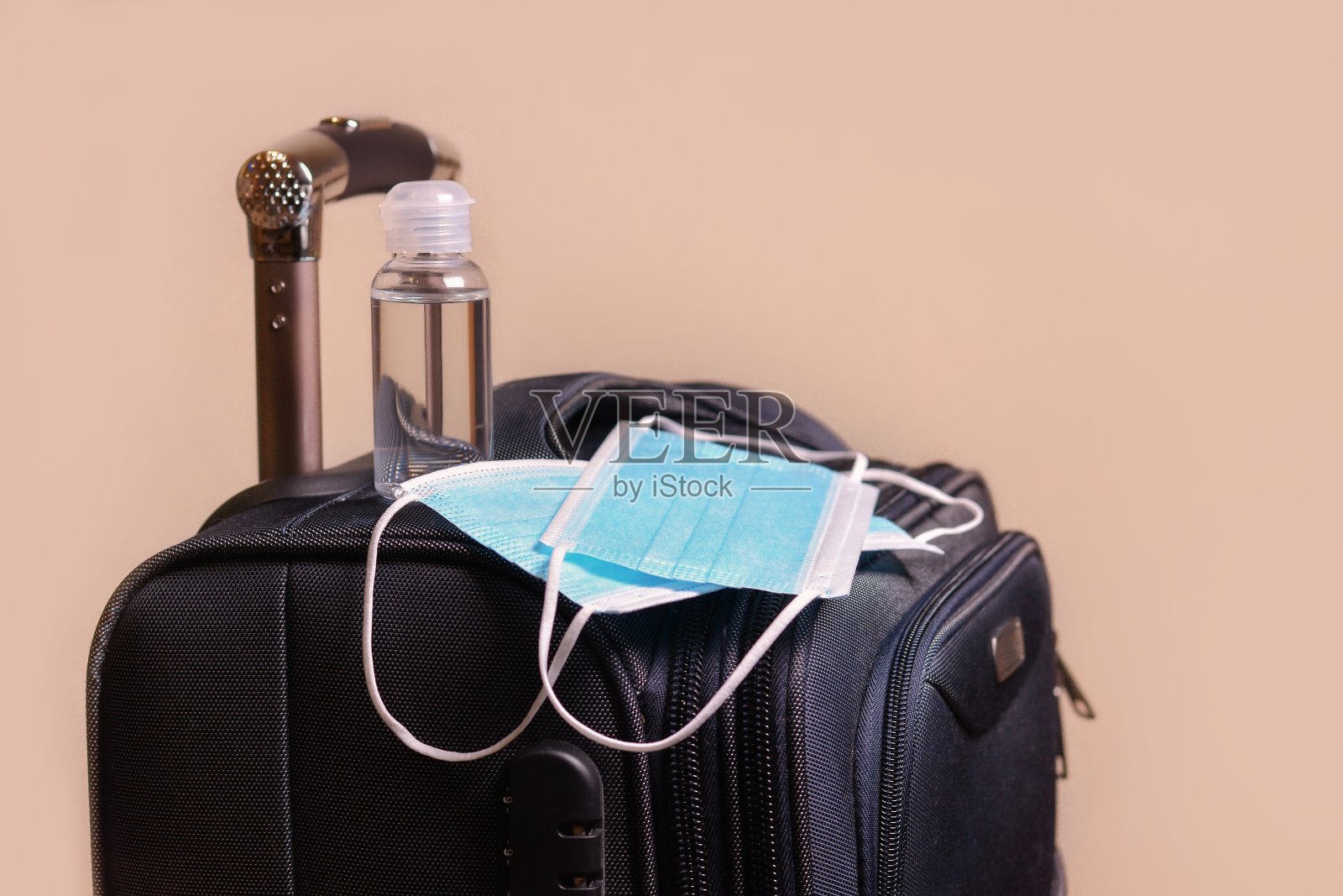 医用口罩,消毒液,浅色背景上的行李箱。旅行、度假、冠状病毒、Covid-19、大流行、隔离、安全度假。照片摄影图片
