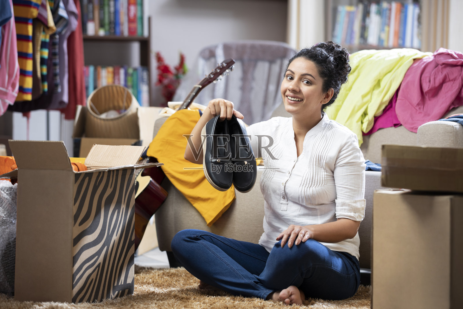 一个年轻妇女的照片显示鞋类坐在地板地毯附近的纸箱室内:库存照片照片摄影图片