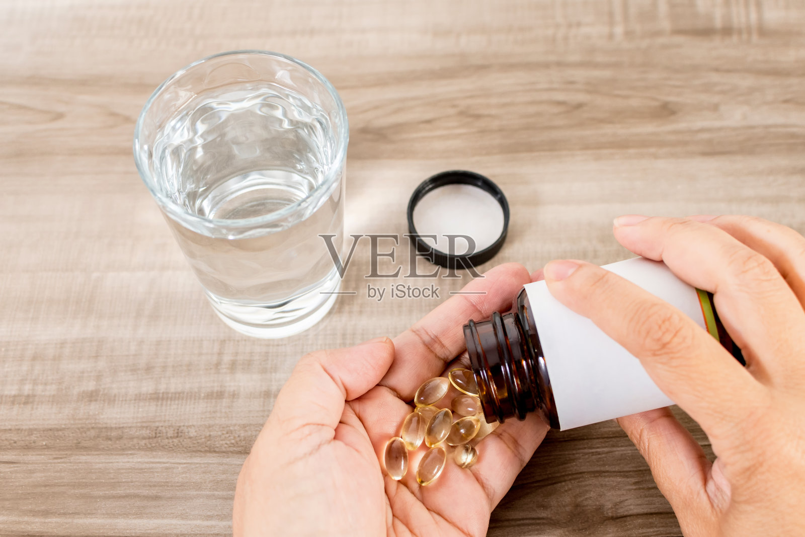 女人手拿药丸和一杯水放在木桌上照片摄影图片