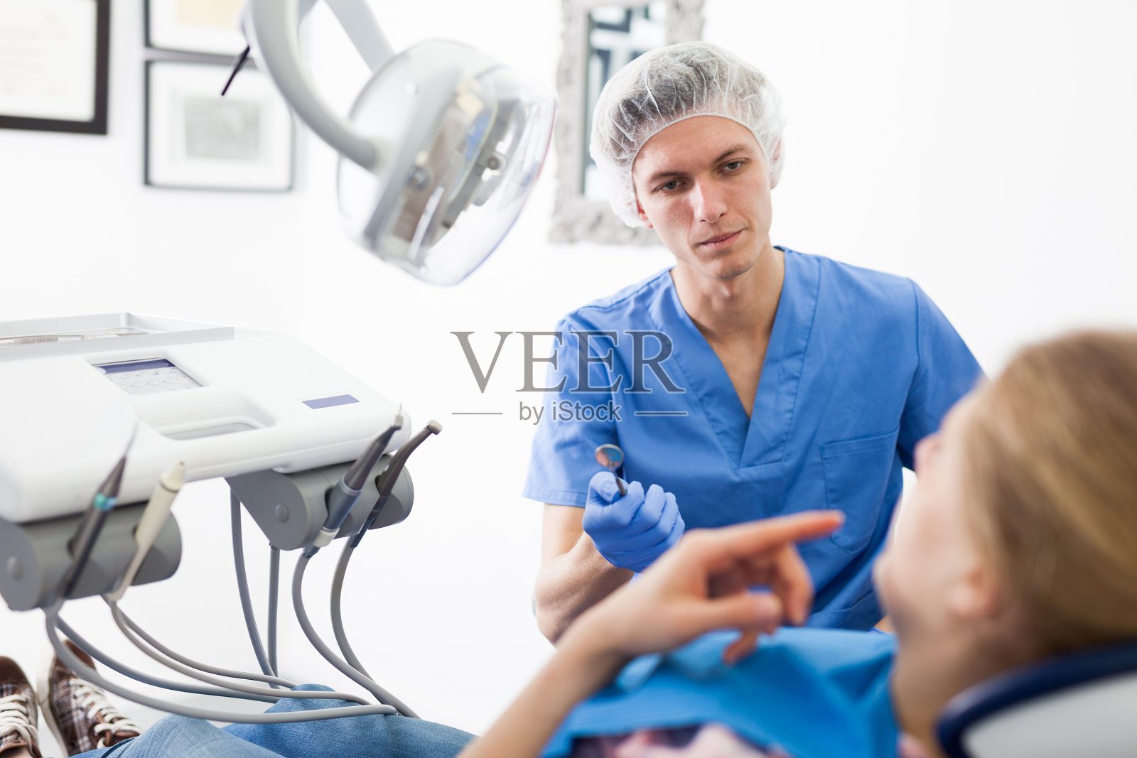 穿制服的男牙医正在牙科诊所为女牙医检查照片摄影图片