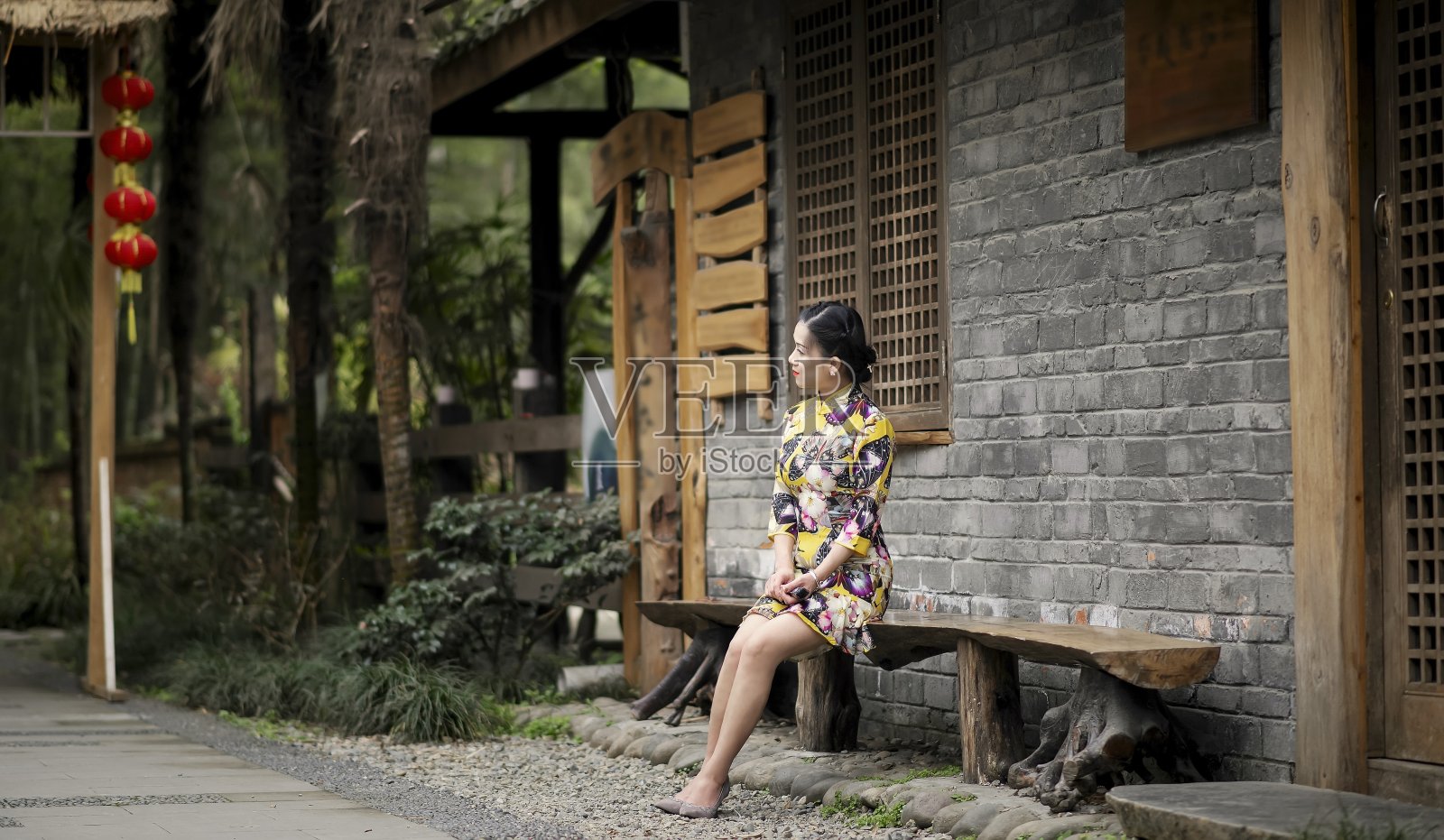 一位身着旗袍的妇女坐在一所老房子前照片摄影图片