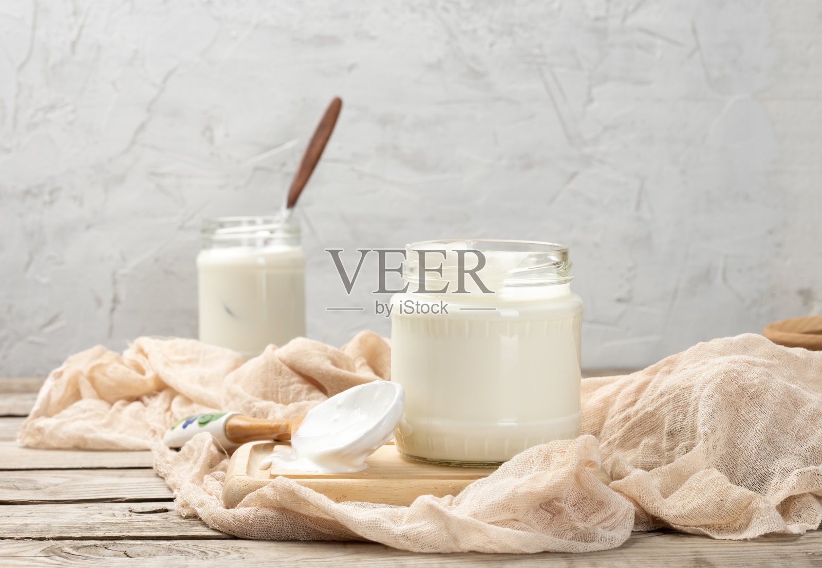 自制的酸奶装在一个透明的玻璃罐子里,放在一张木桌上照片摄影图片