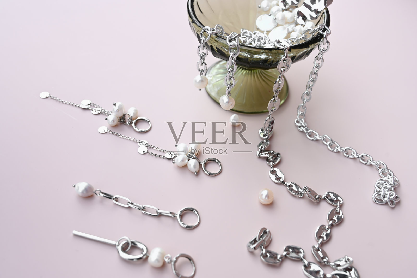 玻璃高脚杯与时尚的珠宝,不同的耳环和链条在柔和的背景。珠宝展示创意照片摄影图片