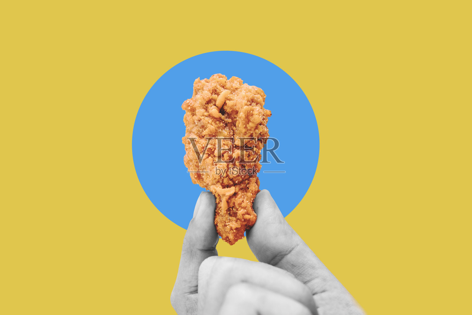 手握炸鸡腿,以蓝黄色为背景照片摄影图片