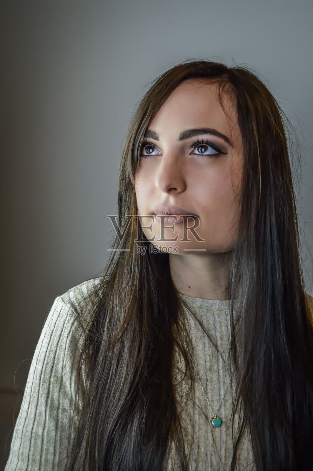 一个美丽的年轻女子的肖像与长棕色头发与梦幻的目光远离照片摄影图片