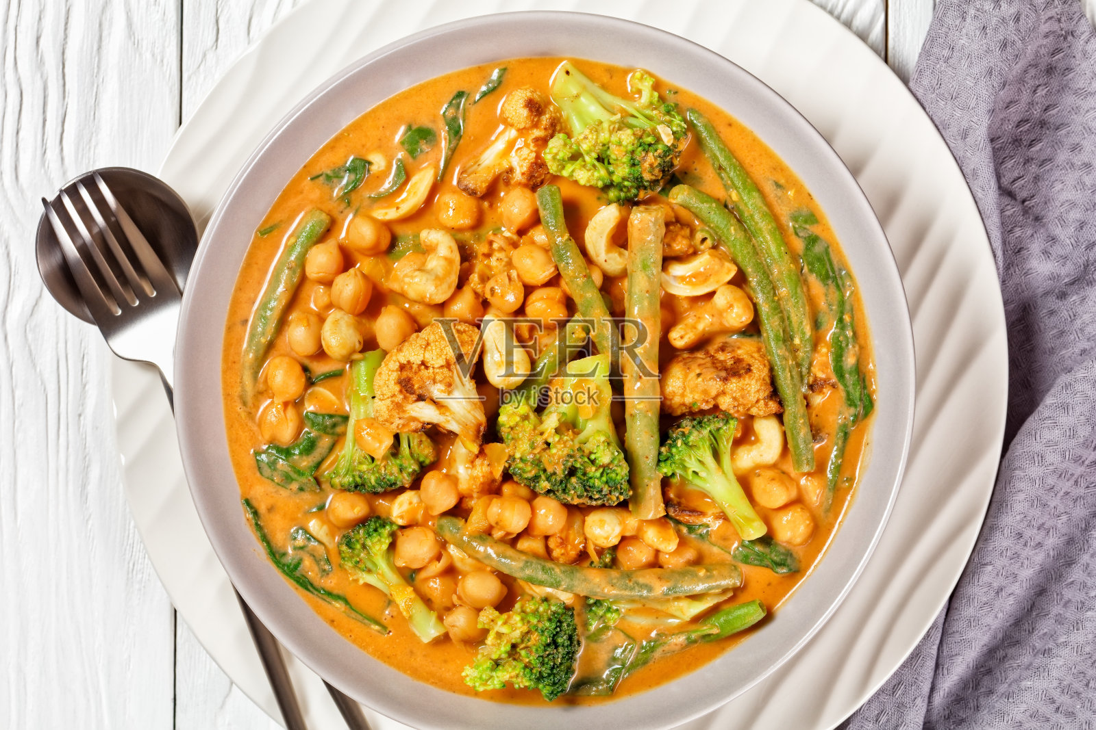 素菜椰咖喱与鹰嘴豆,青豆,花椰菜和花椰菜花在一个碗在一个白色的木桌上,平铺,特写,印度菜照片摄影图片