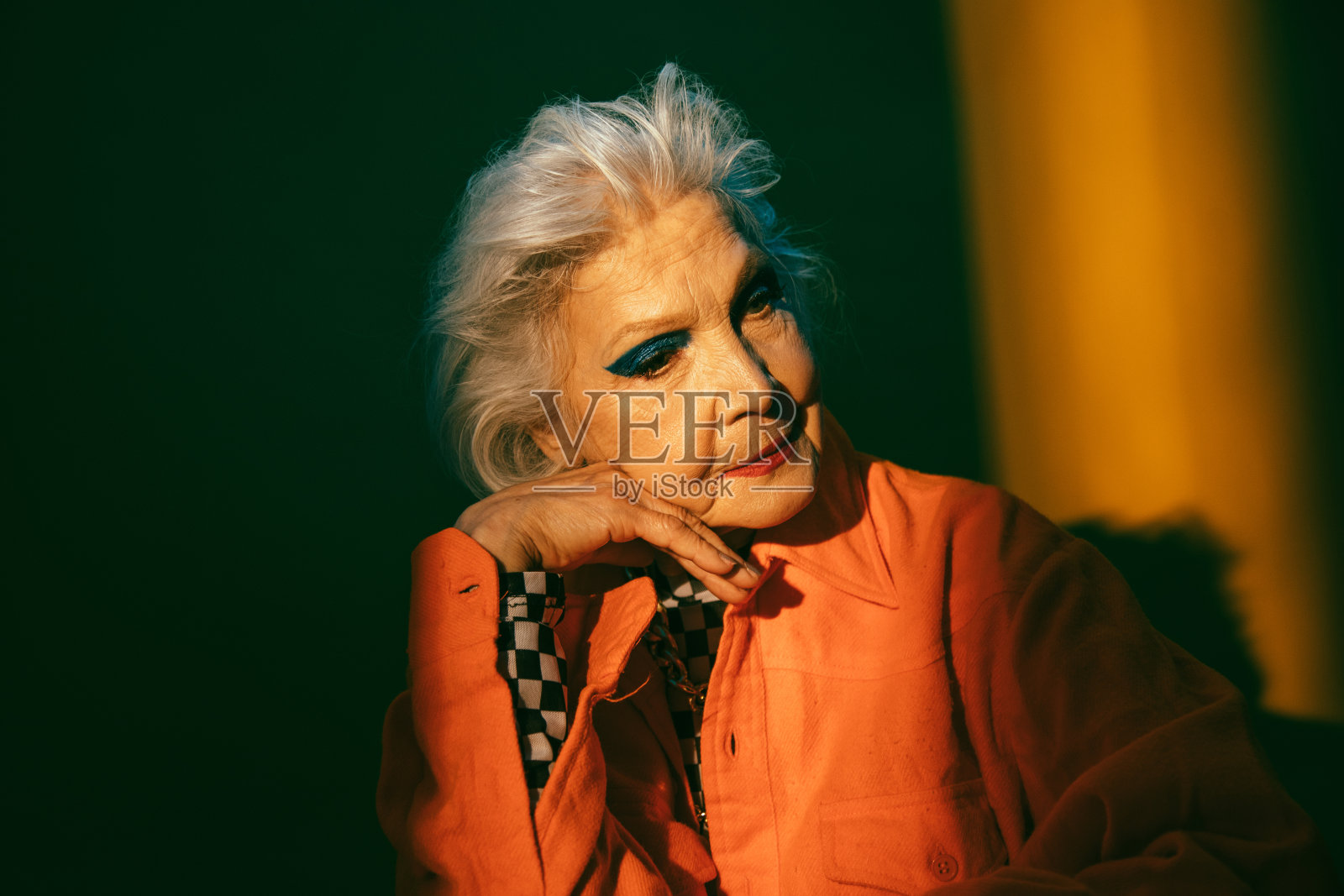 女人与生动的化妆支撑她的头在她的手和看别处照片摄影图片