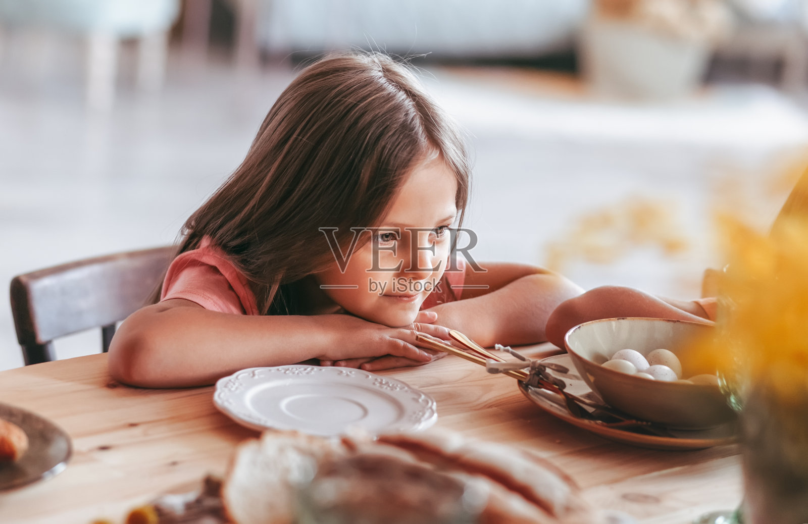 小女孩坐着,沉思地看着餐桌。照片摄影图片