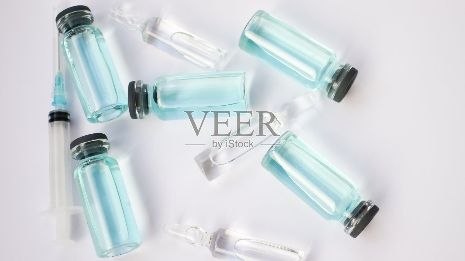 小瓶疫苗,俯视图的玻璃安瓿与透明和蓝色液体躺在白色背景,全球疫苗概念照片摄影图片